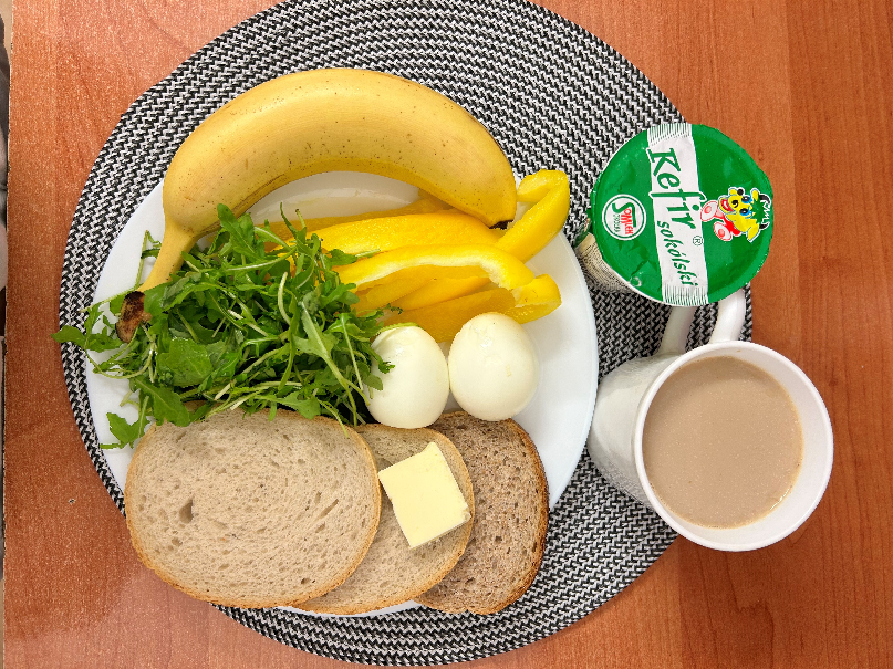 Na zdjęciu: Kefir 2% tł., Kawa zbożowa z mlekiem, Chleb mieszany pszenno-żytni, Chleb Graham, Masło extra 82%, Jajko gotowane, Rukola, Banan, Papryka świeża